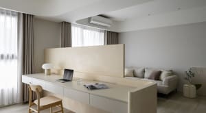 A minimalist living room with neutral tones, featuring a integrated desk and seating area