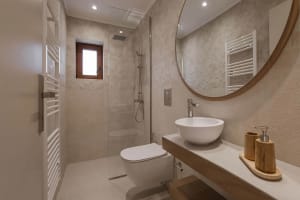 Modern bathroom with walls and floor tiled in a neutral color with a white sink and toilet.