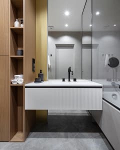 A modern bathroom features wooden cabinets and ceramic tiles.