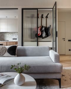 Modern living room with a gray couch, guitars, and a round coffee table.
