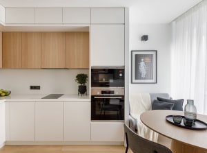 Modern kitchen and living space featuring a sleek, white, minimalist design with wooden accents.