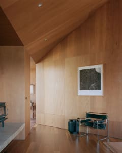 Modern minimalist room with wooden walls and a black chair.