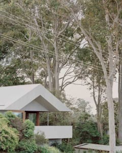 Modern house with a wooden exterior surrounded by trees and power lines.