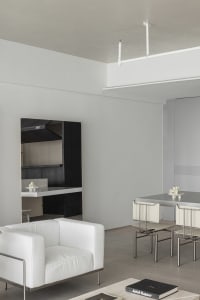 Contemporary minimalist living room features a sleek white leather sofa with metallic frame and black wall panels.