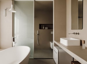 Minimalist bathroom with a white bathtub, concrete walls, and a floating vanity with a white sink.