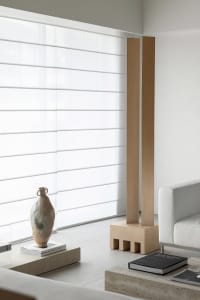 A minimalist living room with a white sofa, concrete coffee table, and large windows.