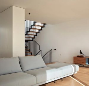 Modern minimalist living room featuring a white sectional sofa, wooden floor, and a wooden cabinet with a black bird figurine