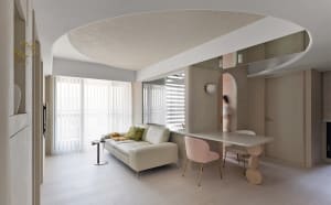 A modern minimalist living room with a white sofa, pink chairs, and a sleek dining table.