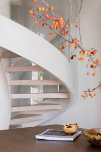 A modern white staircase with wooden steps and glass railings.