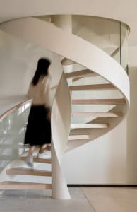 A modern floating staircase constructed from wood, glass, and metal materials.