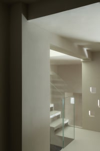 A modern minimalist staircase with glass railings and white concrete steps.