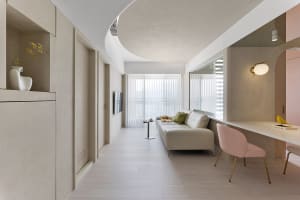 A minimalist living room with concrete walls, a white sofa, and a pink chair.