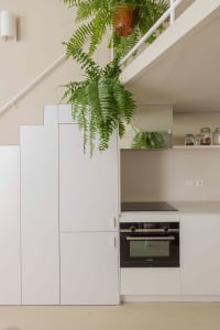 A modern minimalist kitchen featuring concrete cabinets and pendant plants.