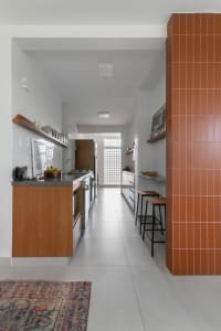 Modern industrial kitchen with white walls, wooden cabinets, and terracotta tiles.