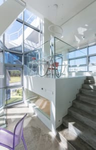 Glass and concrete modern interior design with staircase and seating area.