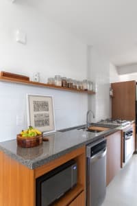 Modern kitchen with granite countertops, wooden cabinets, concrete backsplash, and spice jars on the shelf.