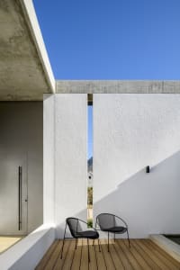 Modern patio with concrete walls and black wire chairs.