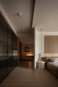Modern bedroom featuring wooden flooring, sleek black wardrobe, and minimalist design elements.