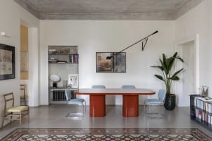 A modern dining room with a rectangular table featuring cylindrical concrete legs, surrounded by blue chairs and adorned with