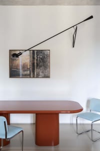 A modern dining room with a matte black dining table, blue chairs, and a minimalist artwork hanging on the wall.