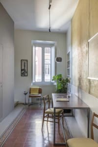 A minimalist, industrial-style office space featuring a modern metal desk, metal chairs, and a glass window.