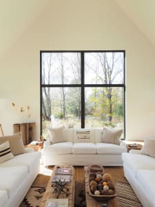 A minimalist living room featuring a large window overlooking a natural outdoor landscape.