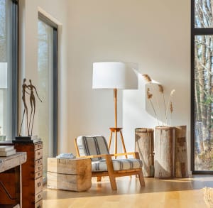 An industrial-style living room with a wooden floor, a striped chair, a tall floor lamp, and decorative wooden blocks.