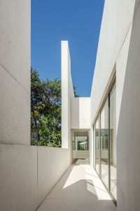 A minimalist white concrete exterior features seamless lines and large glass windows.