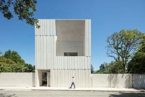 Modern residential building with a white, minimalist exterior made of concrete.
