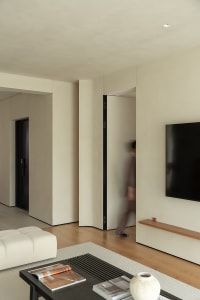 A modern minimalist living room with neutral tones and wood finishes.