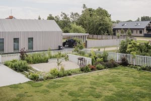 Modern residential exterior with wooden panels and metal roof and fence.