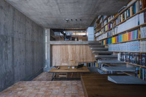 An image depicting a modern office space featuring a concrete bookshelf and a wooden desk with a laptop.