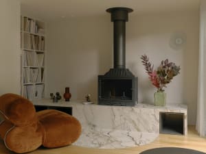 A minimalist living room featuring a marble fireplace and modern furniture.