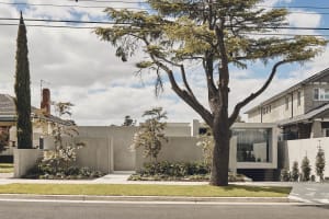 A modern house with a concrete exterior featuring large glass windows.