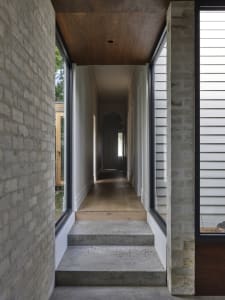 A minimalist entryway featuring wooden walls and flooring, with large windows on either side.