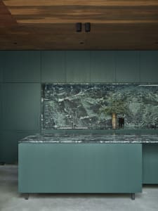 Contemporary kitchen with green marble countertops and backsplash, dark green cabinetry.