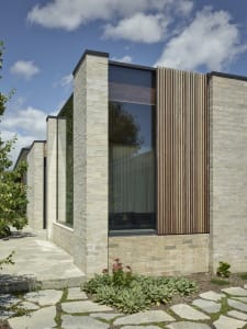 Modern house exterior featuring brick, glass, and wooden elements.