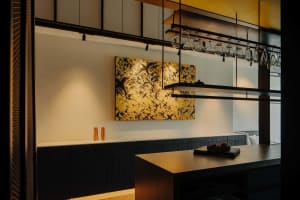 Modern design elements, including a floating shelf, hanging glasses, and yellow wall accent, in a kitchen bar setting.