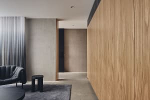 Minimalist residential interior with wood and concrete finishes, featuring a comfortable seating area and a modern aesthetic.