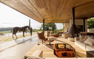 A modern living room featuring wooden furniture and large windows overlooking a serene outdoor landscape.