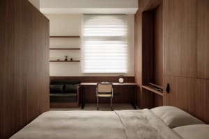 A minimalist bedroom with wooden walls and a white bed.