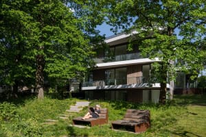 Modern residential building exterior with wooden accents, glass windows, and metal elements.