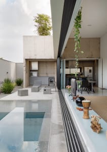 A modern residential swimming pool with concrete walls and a glass area.