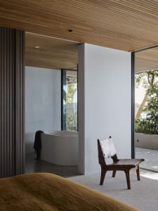 Industrial bathroom with concrete walls and floor, featuring a standalone bathtub next to large windows.