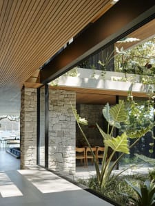A modern residential interior featuring stone, wood, and glass materials.