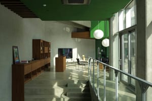 An industrial-style office studio with concrete walls and floors, featuring minimalist furniture and large windows.