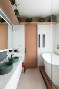 Modern minimalist bathroom interior with white tiles, concrete floor, and green plants.