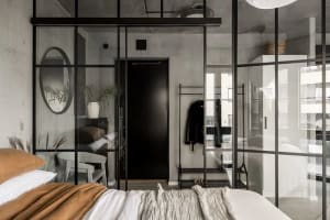 Minimalist bedroom featuring glass walls, concrete floors, and metal accents