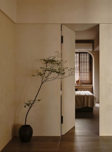 A minimalist bedroom with a bed, bedside table, and wooden floor and walls.