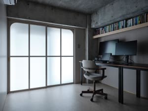 A minimalist home office with concrete walls, a desk, and a sliding frosted glass door.